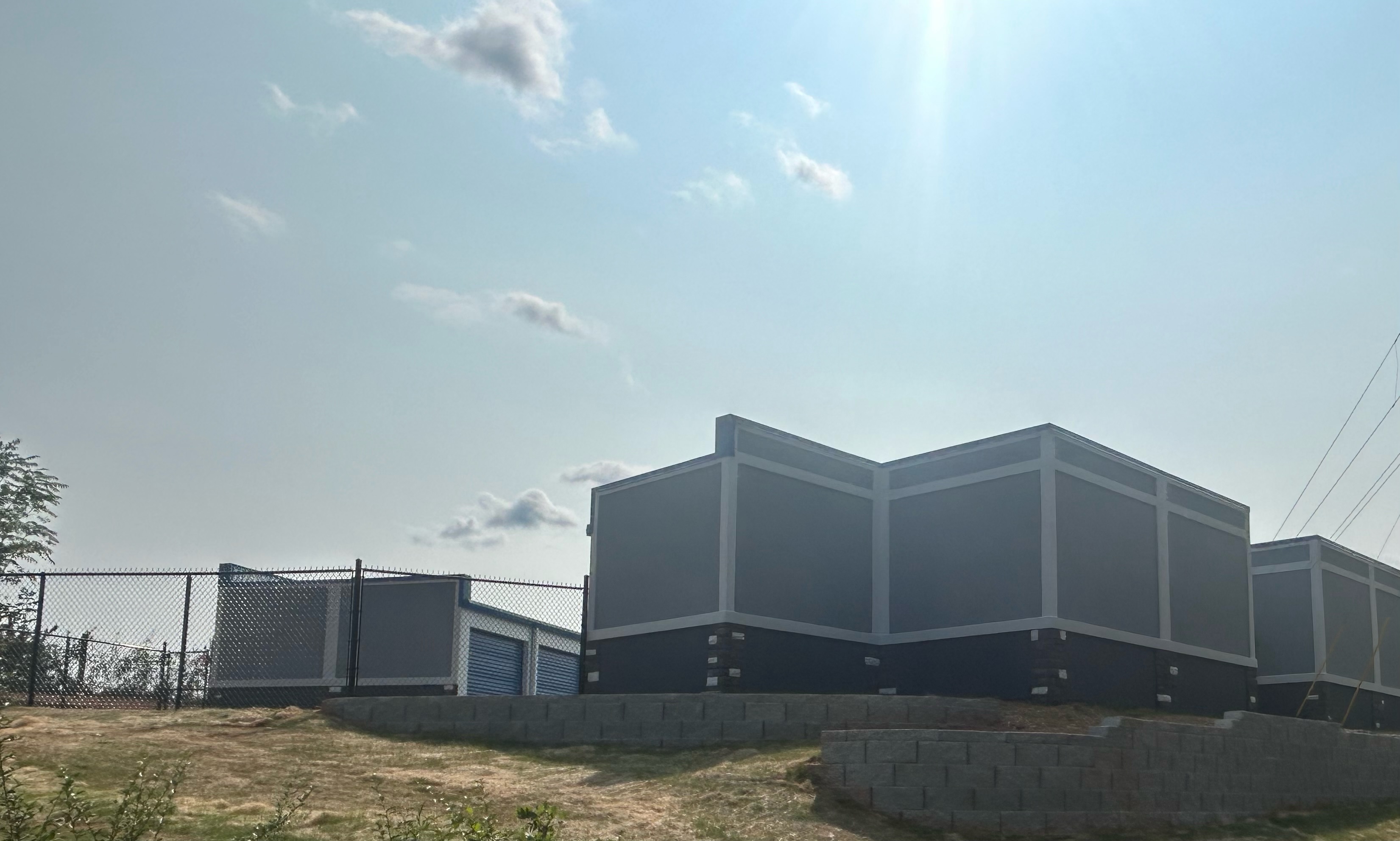 Modern gray and white storage buildings under a bright sky